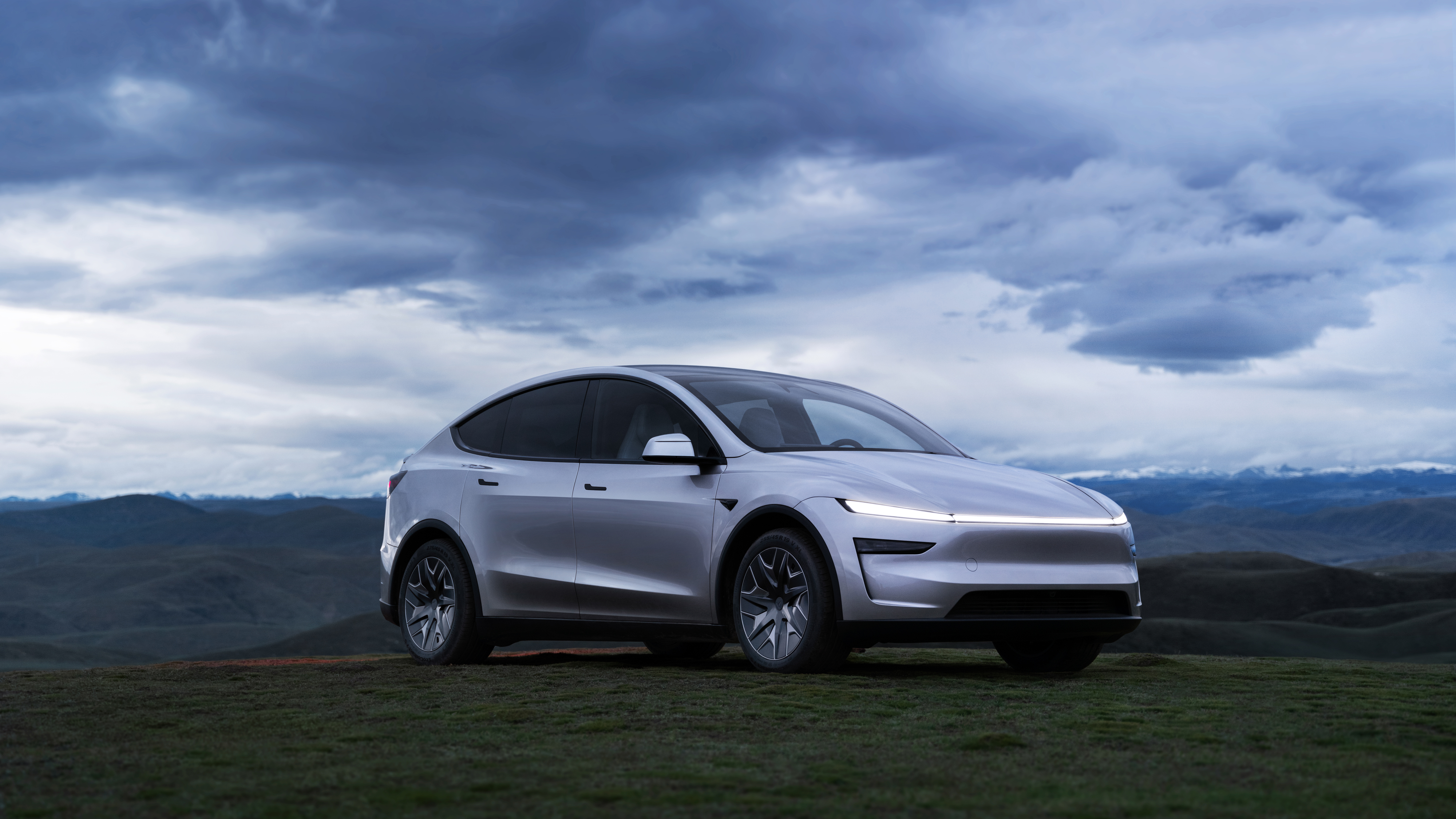 The Model Y L on the road — the stretched proportions read as purposeful rather than awkward, helped by the flush door handles and single-piece light bar up front. Image: Tesla