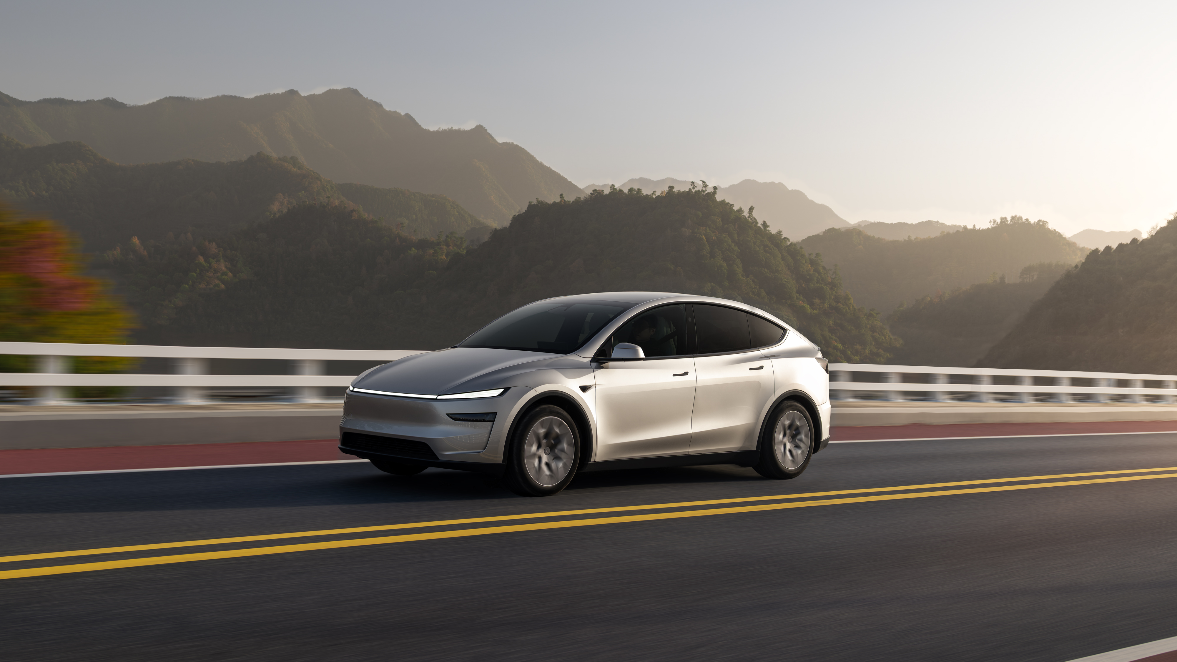 The Model Y L on an open road — EPA-estimated 325 miles of range makes it a credible road-trip vehicle even with a full six-passenger load. Image: Tesla